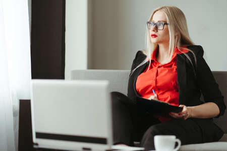 Modern business, freelance work, home workplace. Woman entrepreneur paperworking at her living roomの写真素材