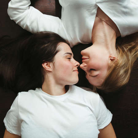 Happiness, equality, human relationships. Two young women laying face to face on the floor. Romantic moments. Lgbt coupleの写真素材