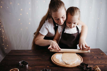 Mother and daughter rolling gingerbread doughの写真素材
