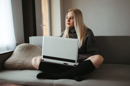 Online shopping, remote work and study. Young woman using laptop in cozy living room. Holiday sale...