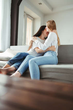 Friendship, romance, happiness. Two young friends embracing in living room. Support and care conceptの写真素材