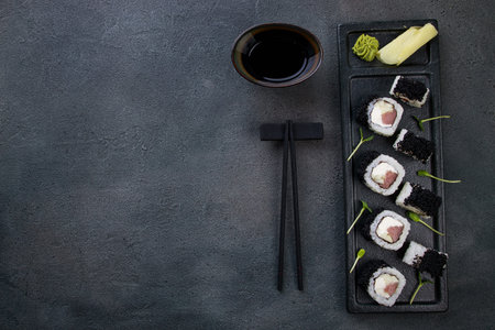 Japanese cuisine, food background. Tasty appetizing sushi rolls with tuna and caviar served on black...