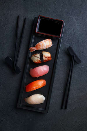 Nigiri sushi set with salmon, grouper, eel, tuna and prawn, flat lay on black plate. Delicious traditional Japanese food, tasty seafood, restaurant concept, food backgroundの写真素材