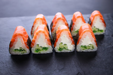Japanese cuisine, food delivery mockup, seafood background. Salmon sushi rolls on slate, copy space....