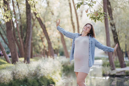 Happy motherhood, healthy pregnancy. Mother and child relation. Young pregnant woman walking in the park breathing fresh air.の写真素材