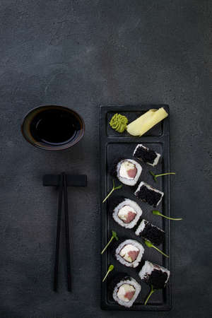 Japanese cuisine, food background. Tasty appetizing sushi rolls with tuna and caviar served on black plate, copy spaceの写真素材