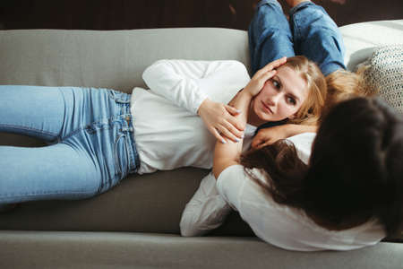 Two young female friends embracing in living roomの写真素材