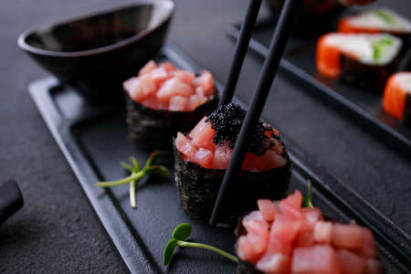 Chopsticks taking gunkan maki sushi from plateの写真素材