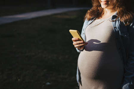 Pregnant woman using mobile phoneの写真素材