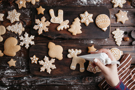 Christmas bakery. Decorating freshly baked gingerbread cookies with icing, view from above. Festive...