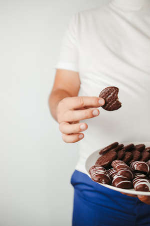 Obesity prevention, healthy lifestyle, diet. fattening food, high-calorie snack. Overweight man eating unhealthy sweet cookiesの写真素材
