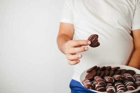 Weight loss, overweight, diet, unhealthy eating. Fat man with plate of chocolate cookies
