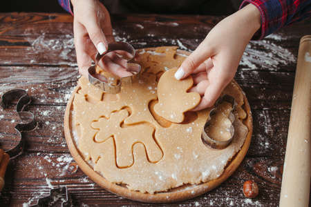 Christmas and New Year holidays preparation. Traditional sweets, celebration food. Woman cutting cookies of raw gingerbread doughの写真素材