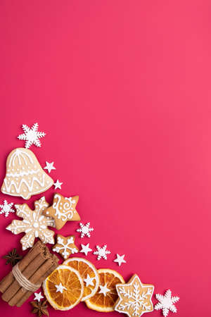 Winter holiday vibes. Frame made of festive decorations, dried oranges, spices and gingerbread on red background. Seasonal background, Christmas, New Year composition. Flat lay, copy spaceの写真素材