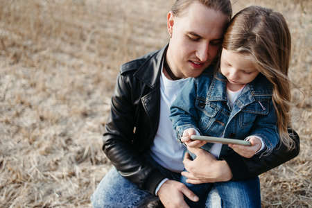 Father and daughter playing games using mobile phone together. Technology and family time conceptの写真素材