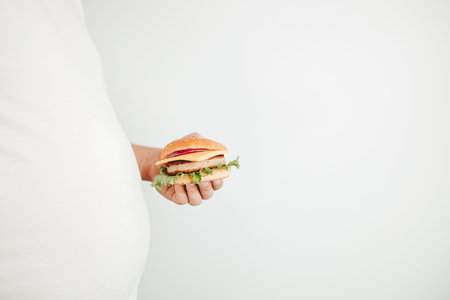 Fast food. Weight loss, diet, unhealthy eating, overeating. Overweight man with hamburger copy space