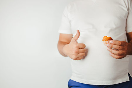 Balanced ration, diet, counting calories. Low calorie meals. Overweight man snacking with cupcake