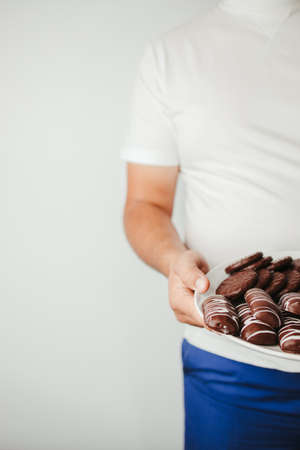 Fat man with plate of chocolate cookiesの写真素材