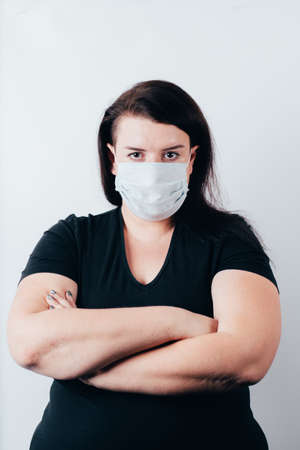 Social distancing. New normal concept. Woman in medical mask folding arms on chest looking at copy spaceの写真素材