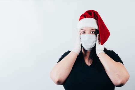 Christmas in corona crisis time. Shocked overwhelmed woman wearing a face mask and gloves. Mockup with copy spaceの写真素材