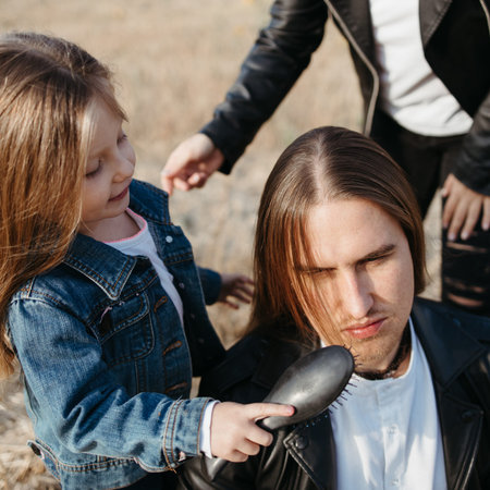 Mother and daughter braiding fathers long hair