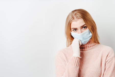 Bored sad young woman wearing medical mask. Self isolation, quarantine restrictions, new normal conceptの写真素材