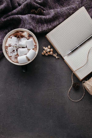 Cozy home desk table with knitted sweater, cocoa cup, smart phone with blank screen on gray stone background. Autumn, fall, winter composition. Nordic hygge style conceptの写真素材