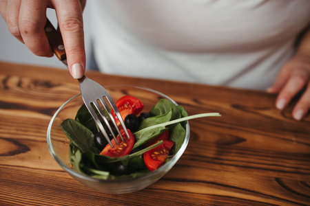 Dieting, healthy low calorie food, weight losing concept. Overweight woman eating healthy vegetable salad from the bowlの写真素材