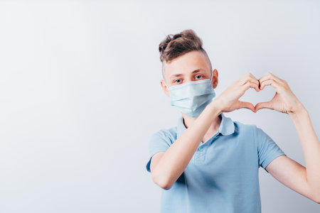 Love and appreciation, support concept. Admire and approval. Boy in medical mask making heart gestureの写真素材