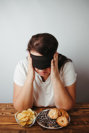 Woman with closed eyes eating unhealthy food. Intuitive nutrition, mindfulness, conscious eating. Diet breakdownの写真素材