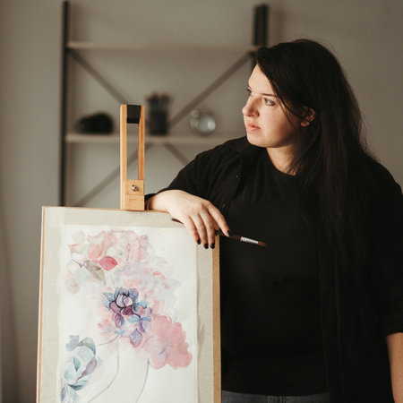 Illustrator, artist or designer at work. Young creative woman standing at home studio with watercolor painted floral pattern sketchの写真素材