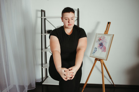 Home workout. Overweight woman doing stretching exercises in her living room. Weight loss, activity and healthy lifestyleの写真素材