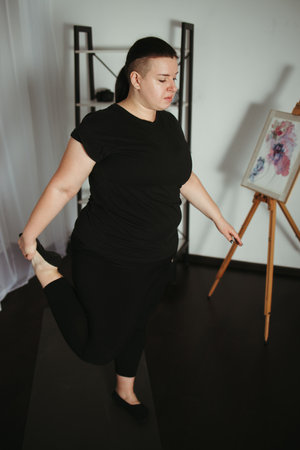 Overweight woman doing yoga in her living room. Yoga beginner workout, home training, weight loss conceptの写真素材