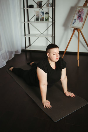 Overweight woman doing yoga exercise at home. Yoga for beginners. Weight loss