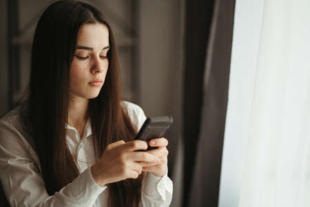 Remote work, freelance, stay at home, business concept. Young woman talking to business partners using smart phone working at home officeの写真素材