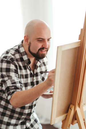 Modern art. Inspiration and creativity, hobby concept. Young painter doing easel drawing at art studio. Artist workshop. Illustrator at workの写真素材