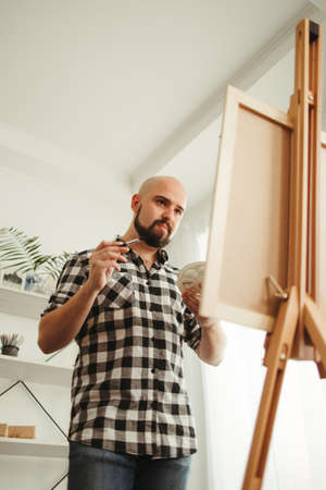 Young painter doing easel drawing at art studioの写真素材