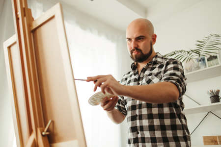 Young man doing watercolor painting at home studioの写真素材