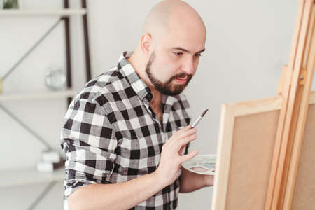 Young painter doing easel drawing at art studioの写真素材