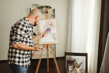 Young man doing watercolor painting at home studioの写真素材