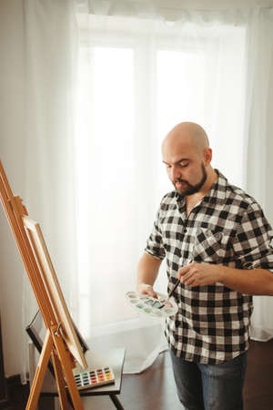 Artist at work. Young man doing easel drawingの写真素材