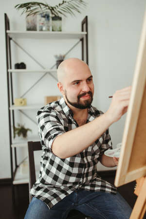Artist at work. Young man doing easel drawingの写真素材
