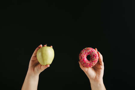 Diet, healthy lifestyle, weight loss, eating habits concept. Choosing between balanced and junk food. Cheat meal, dieting breakdownの写真素材