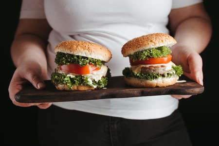 Fast food. Overeating. Weight loss diet, unhealthy eating. Overweight woman with hamburgersの写真素材