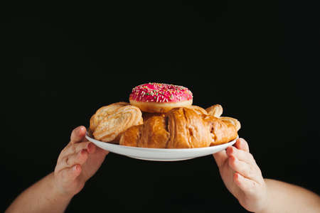 Diet, healthy lifestyle, weight loss, eating habits concept. Hands holding plate with unhealthy sugary sweets, copy spaceの写真素材