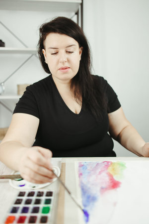 Art therapy, stress relief, creative hobby. Young concentrated woman do watercolor drawing, holding...