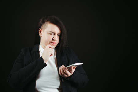 Doubtful pensive woman looking at smart phone screen. Sale, decision, special offer, solution search. Background with copy space for advertisingの写真素材