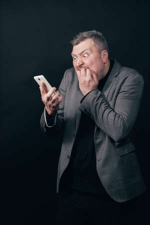 Frustrated scared man with smart phoneの写真素材