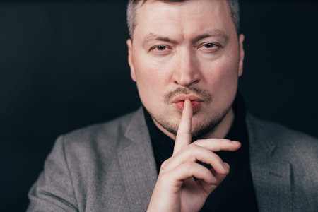 Serious business man showing silence gesture