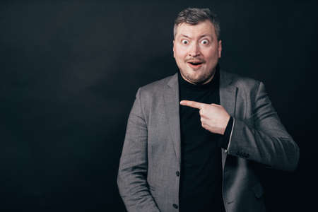 Businessman with funny face pointing at free spaceの写真素材